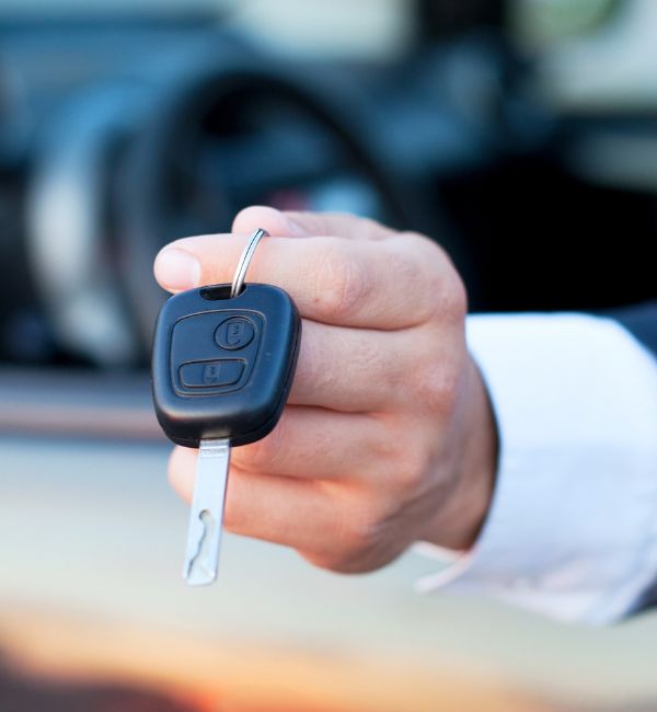 A friendly locksmith handing over a car key, ready to help with lockouts or replacements in Leigh